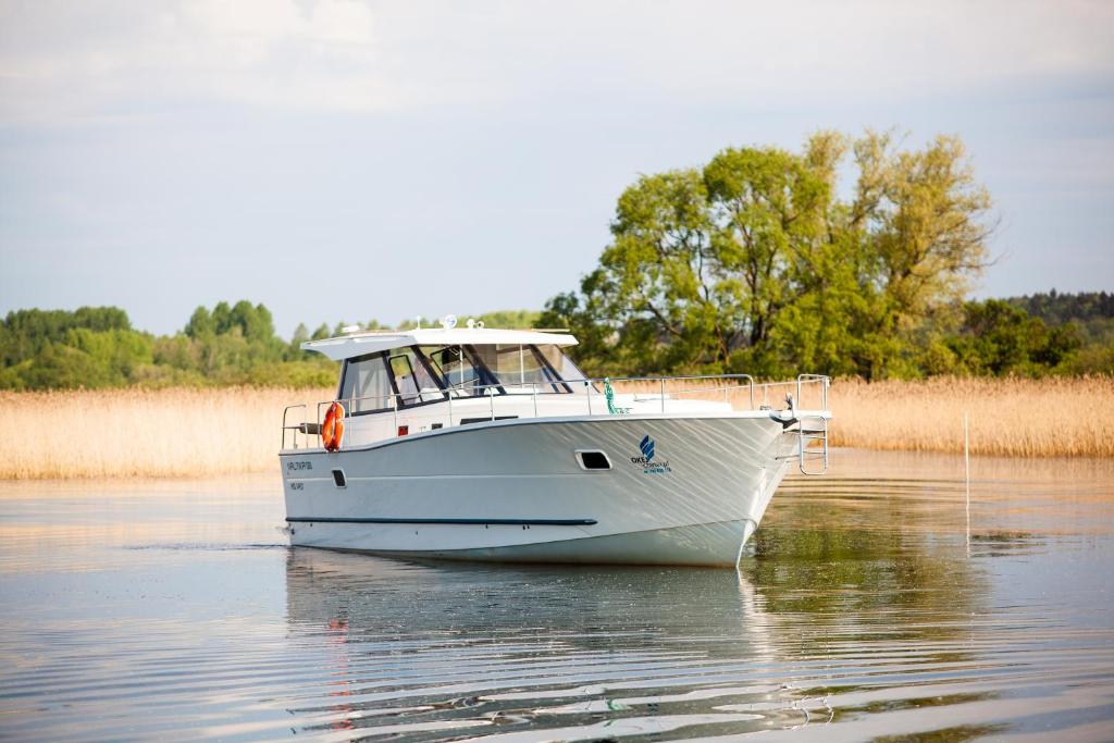 un bote blanco en el agua en un río en Jacht motorowy Nautika 1300 VIP, en Wilkasy