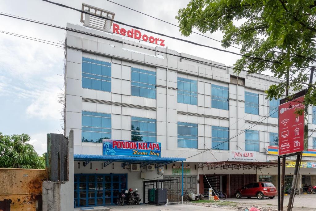 a white building with a red sign on it at RedDoorz near Manhattan Square Medan in Pulauberayan