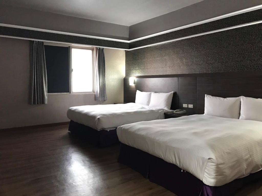 a hotel room with two beds and a window at Long Siang Hotel in Kaohsiung