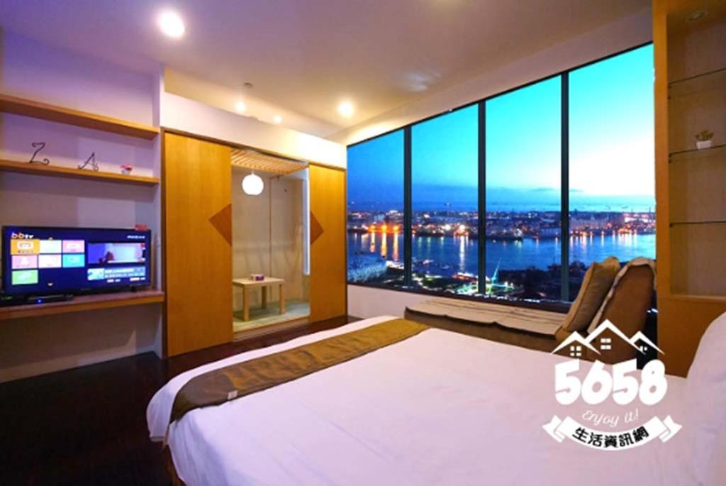 een slaapkamer met een groot bed en een groot raam bij 85 Vacation ApartHotel in Kaohsiung