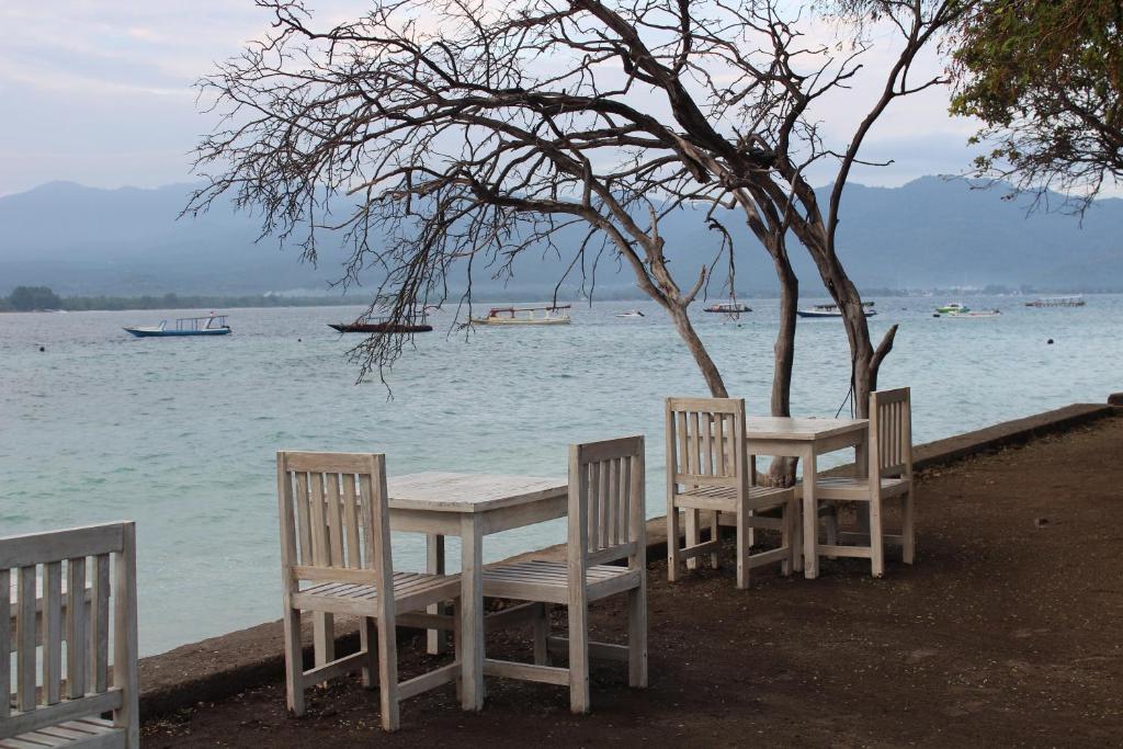 a table and chairs sitting next to the water at Biba Beach Village in Gili Islands