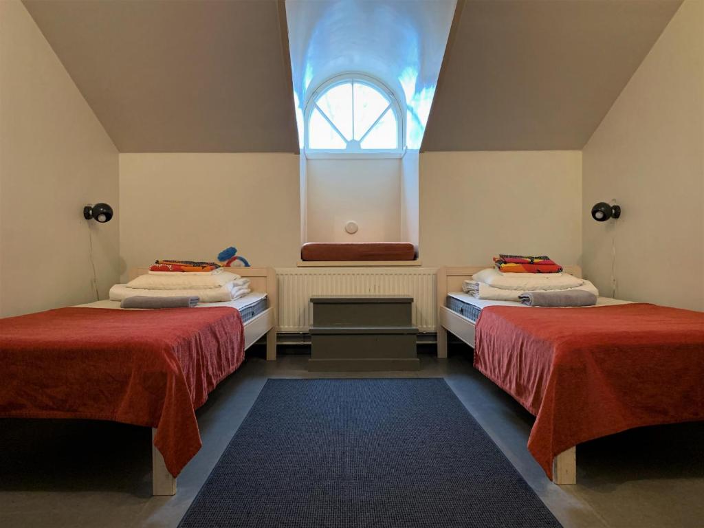 dwa łóżka w pokoju z oknem w obiekcie Hostel Suomenlinna w Helsinkach