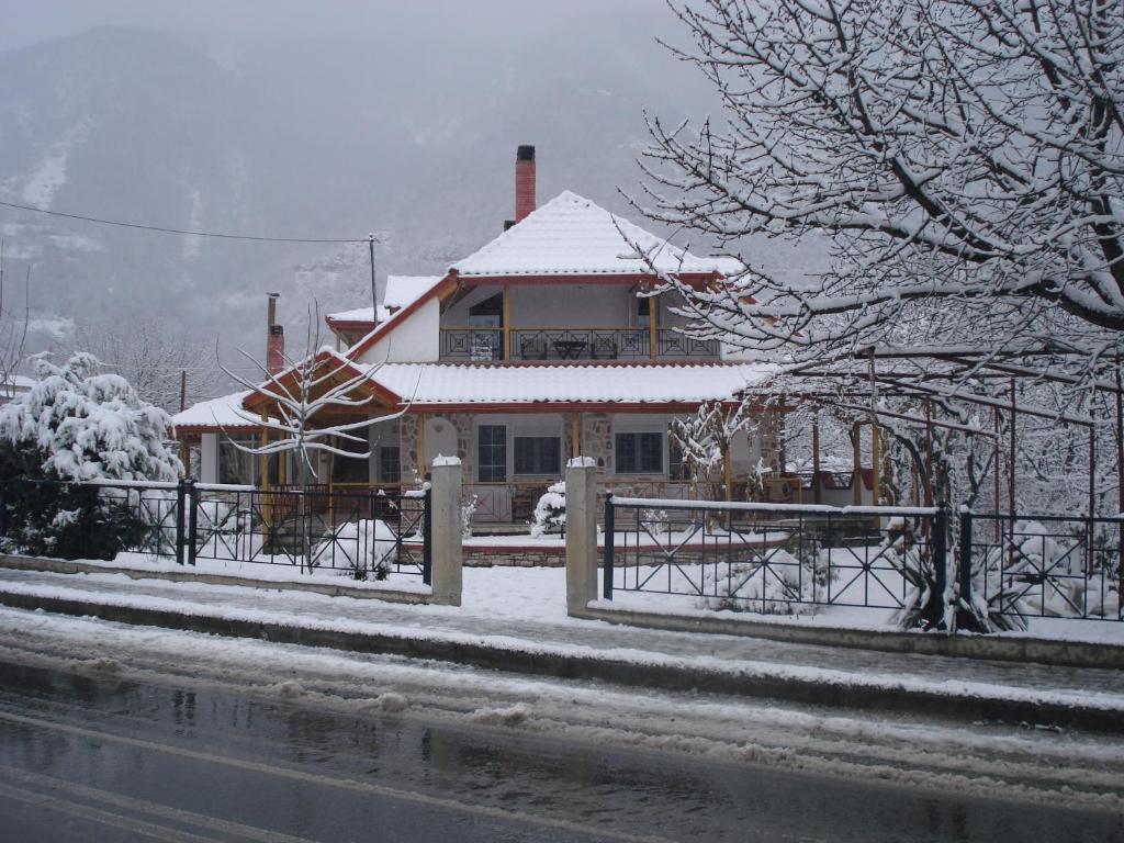 een huis bedekt met sneeuw met een hek bij Guesthouse Agnandi in Kato Loutraki