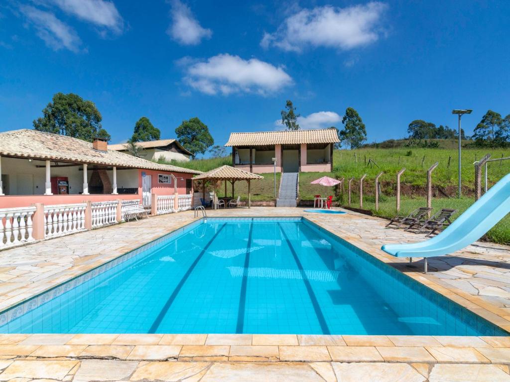 a swimming pool with a slide in front of a house at Hotel Fazenda Morada Do Imperador in Barbacena