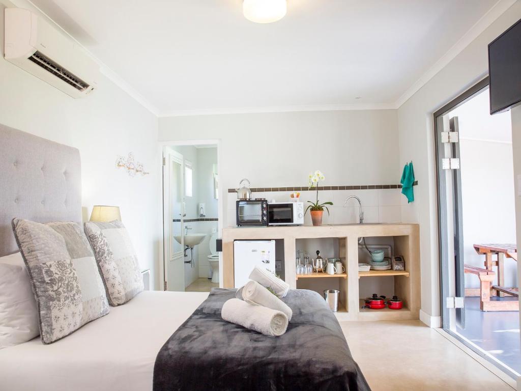 a white bedroom with a bed with towels on it at 401 Rozendal Cottages in Stellenbosch