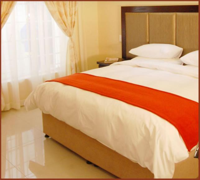 sypialnia z dużym łóżkiem i oknem w obiekcie Booth Suite Hotel Mafikeng w mieście Mahikeng