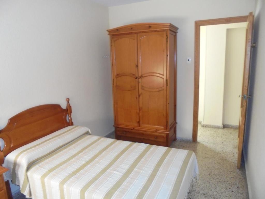 Un dormitorio con una cama y un armario de madera. en Vivienda Turística Argollones 2022, en Almería