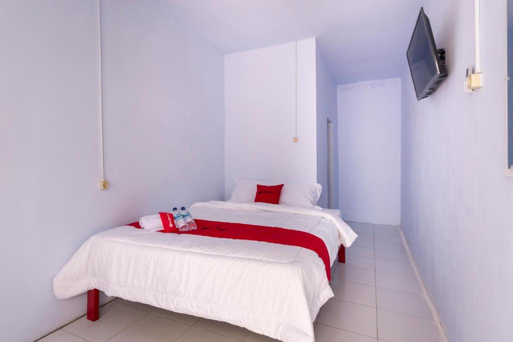 - une chambre avec 2 lits et une télévision murale dans l'établissement RedDoorz Syariah @ Bondowoso City Center, à Bondowoso