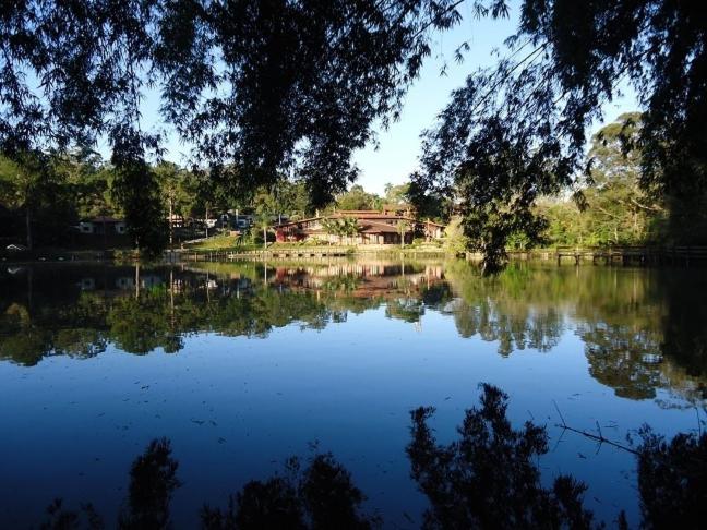 uma vista para um lago com uma ponte ao fundo em Hotel Passarim em Capão Bonito