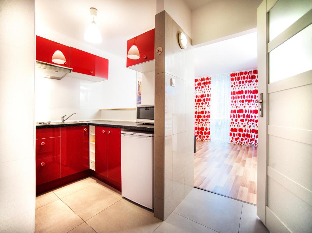 a red and white kitchen with red cabinets at Apartamenty Dobranoc - Centrum in Warsaw