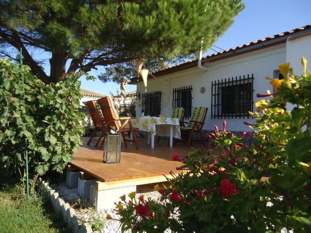 a wooden deck with a table and chairs in a garden at Villa de Limones in Chiclana de la Frontera