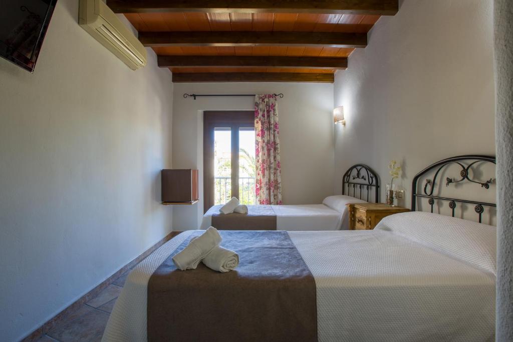 a hotel room with two beds and a window at Hostal Valle Del Sol Alora in Alora