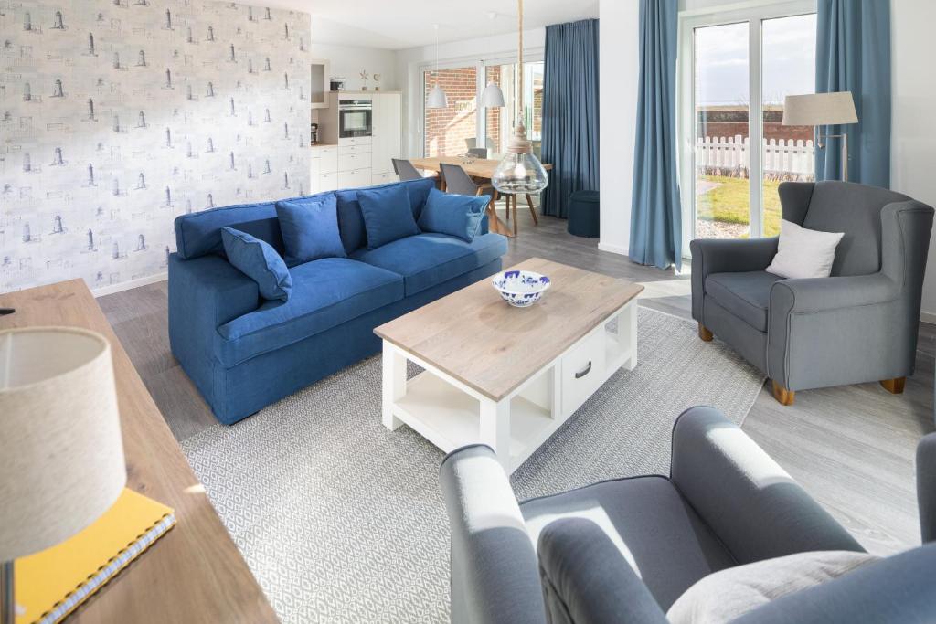 ein Wohnzimmer mit blauen Sofas und einem Tisch in der Unterkunft Deichsonne - mit Wintergarten und Blick Richtung Wattenmeer in Juist