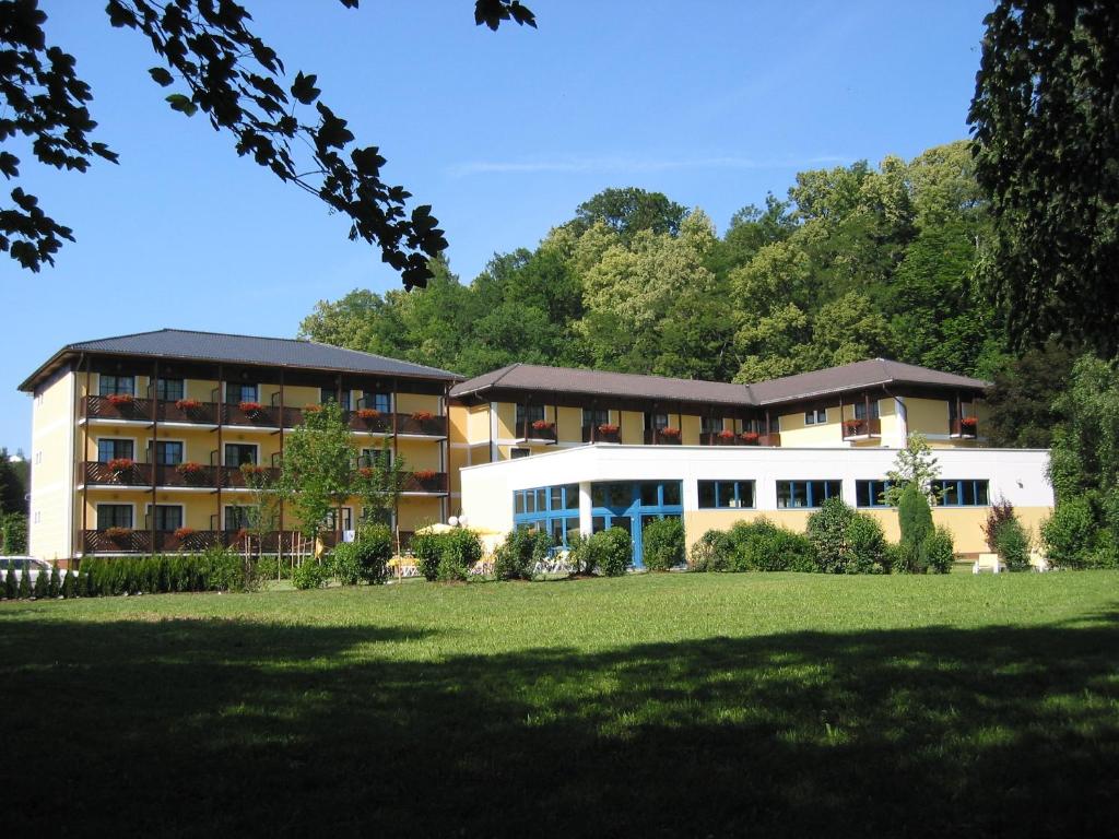 un grand bâtiment avec une pelouse devant lui dans l'établissement Parkhotel zur Klause, à Bad Hall