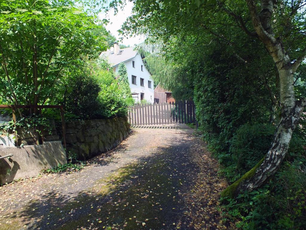 a dirt road with a fence and a white house at Chata Údolíčko in Perštejn