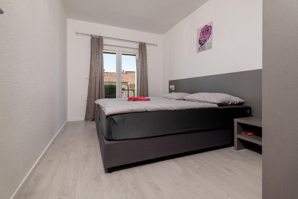 sypialnia z łóżkiem i dużym oknem w obiekcie Apartments & rooms Leon w Neum