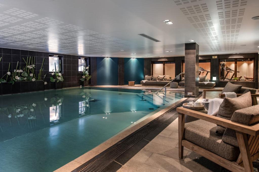 a swimming pool in a hotel lobby with a couch at Manali Lodge by Alpine Residences in Courchevel