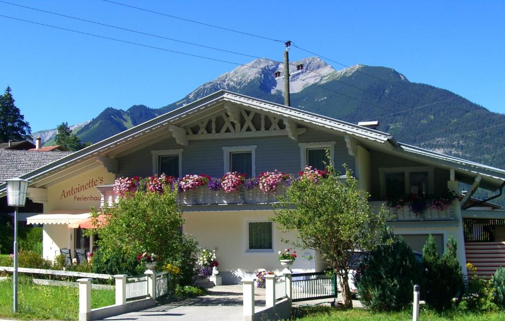 a house with flowers on a balcony with a mountain at Ferienhaus Antoinette in Biberwier