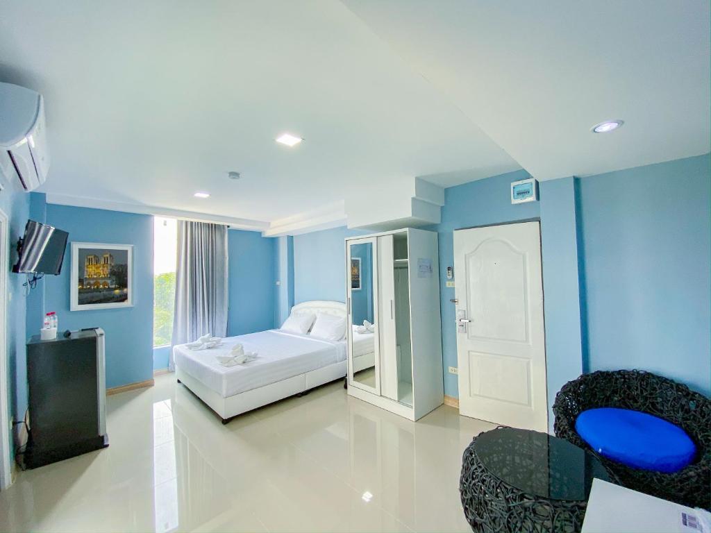 Cette chambre comprend un lit blanc et des murs bleus. dans l'établissement Delighted Bangkok Hotel, à Bangkok