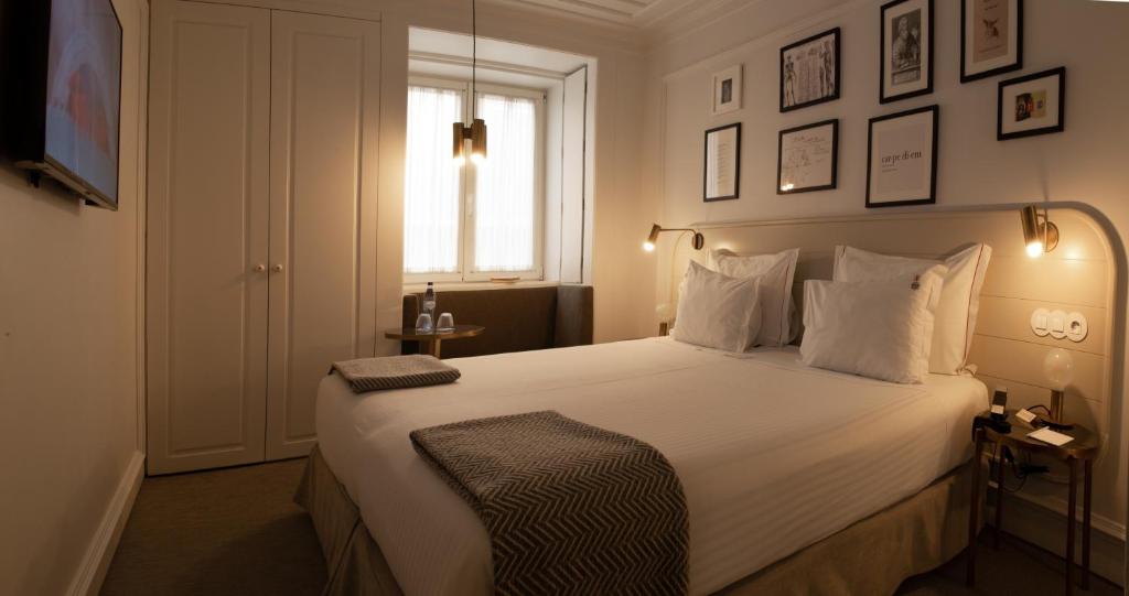 a bedroom with a large white bed and a window at Lisboa Pessoa Hotel in Lisbon