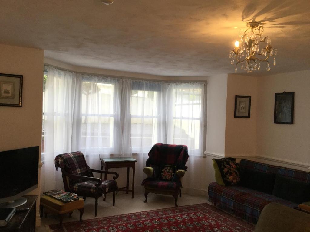 ein Wohnzimmer mit einem Sofa, Stühlen und einem Kronleuchter in der Unterkunft Garden flat 1 in Llandudno