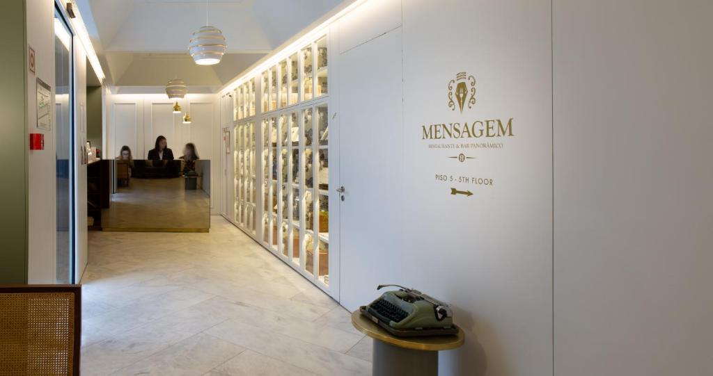 A hotel passage frames a reception desk beside a glass-fronted display wall.