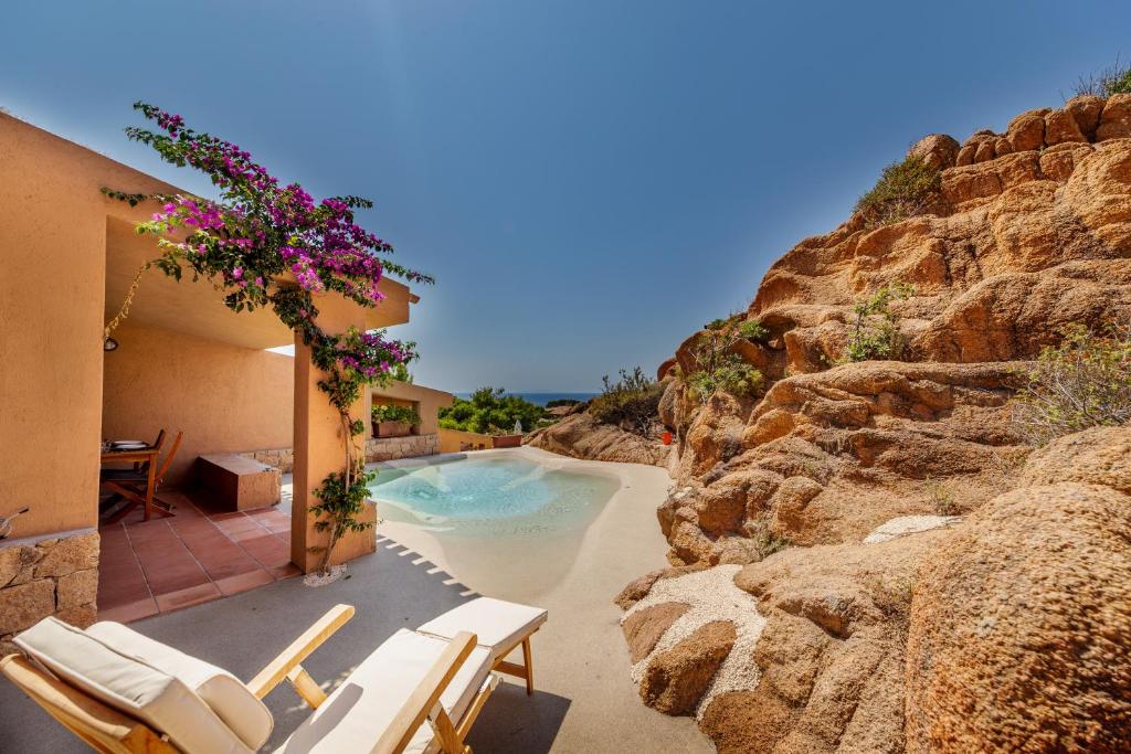 una piscina con sillas y una pared de roca en Costa Paradiso Resort en Costa Paradiso