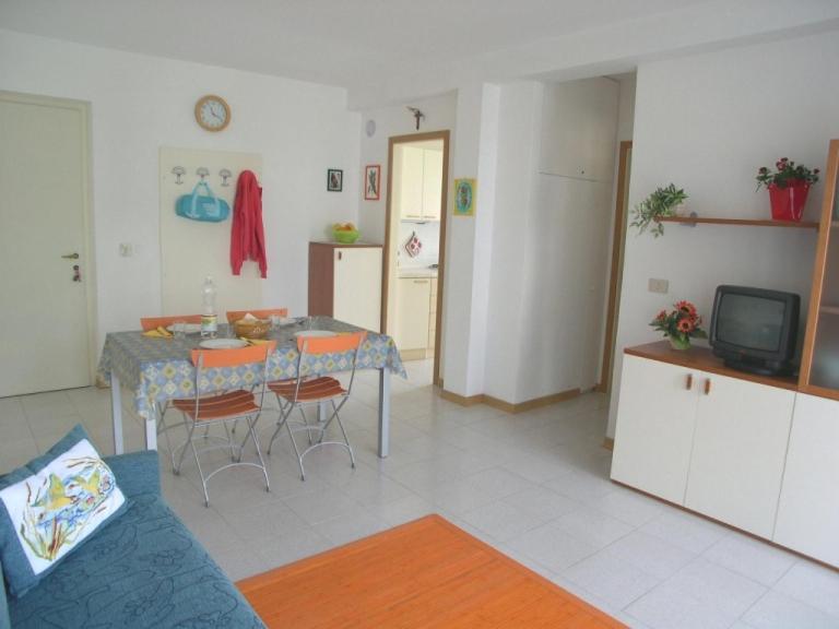uma sala de estar com uma mesa e cadeiras e uma televisão em Villa Clivia em Grado