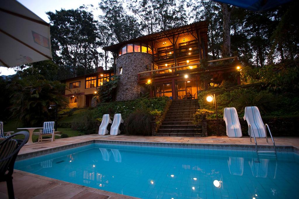 a house with a swimming pool in front of a building at Bromélia Sabiá & Cia in Teresópolis