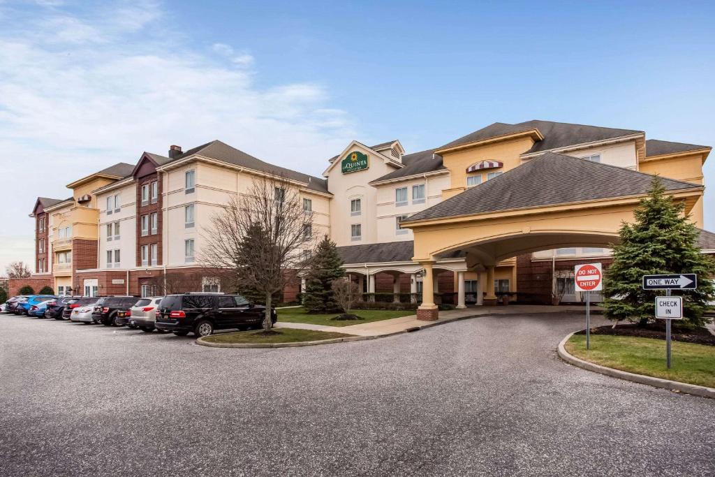 a large hotel with cars parked in a parking lot at La Quinta by Wyndham Islip - MacArthur Airport in Bohemia