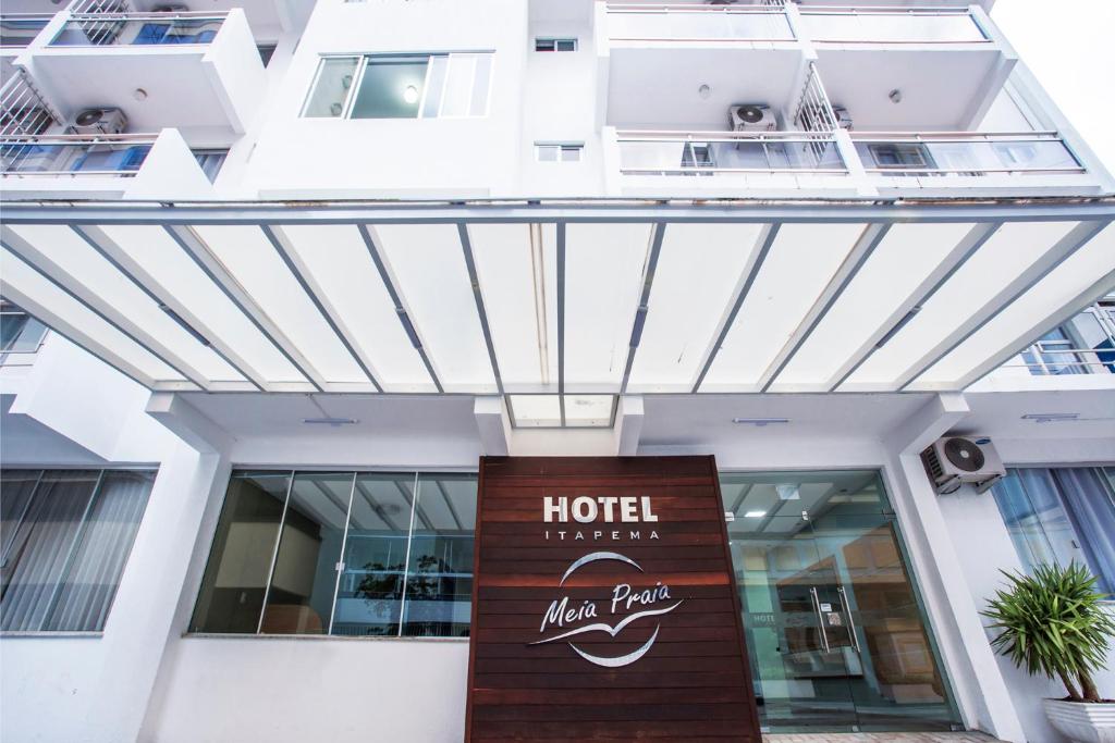 a hotel with a sign in front of a building at Hotel Itapema Meia Praia in Itapema