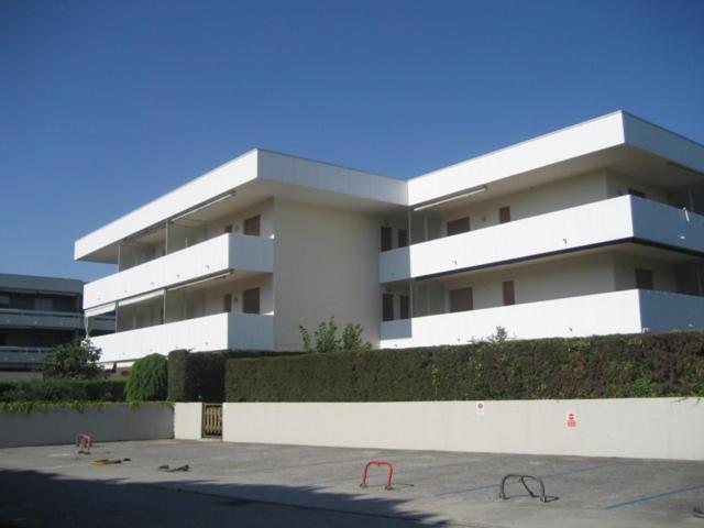 un gran edificio blanco frente a un aparcamiento en Condominio Piscina, en Grado