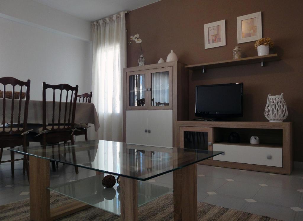 un salon avec une table en verre et une télévision dans l'établissement CASA AGUILAR, à Castelserás