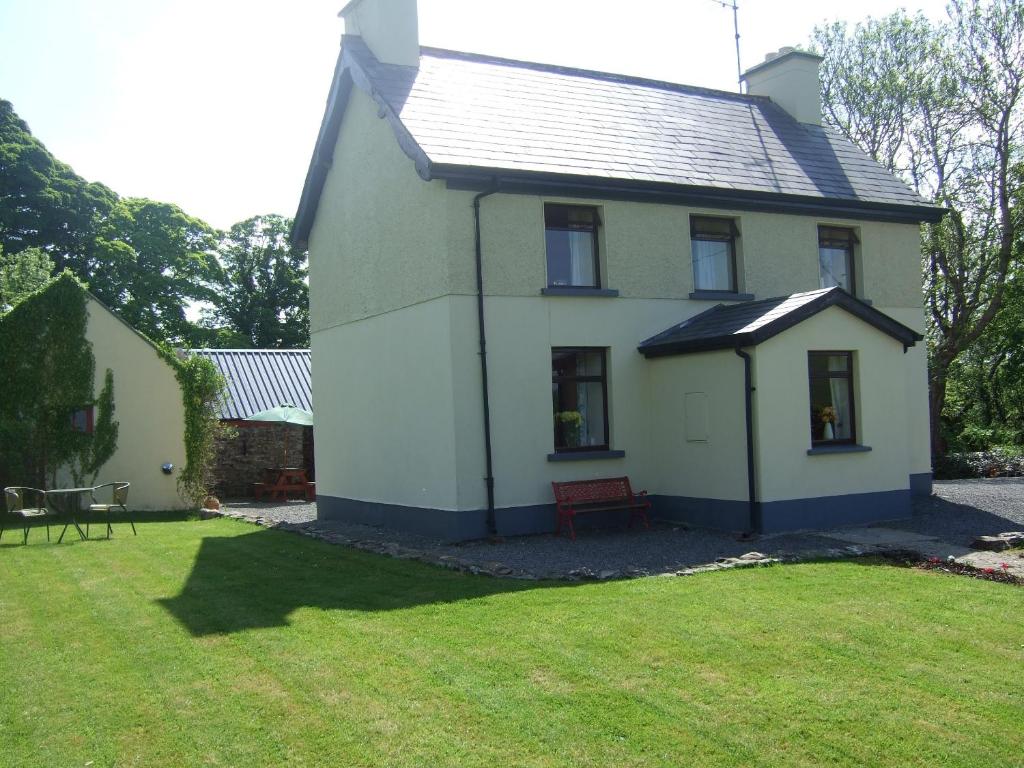 a small white house with a grass yard at James Tymon Self-Catering Cottage in Gorteen