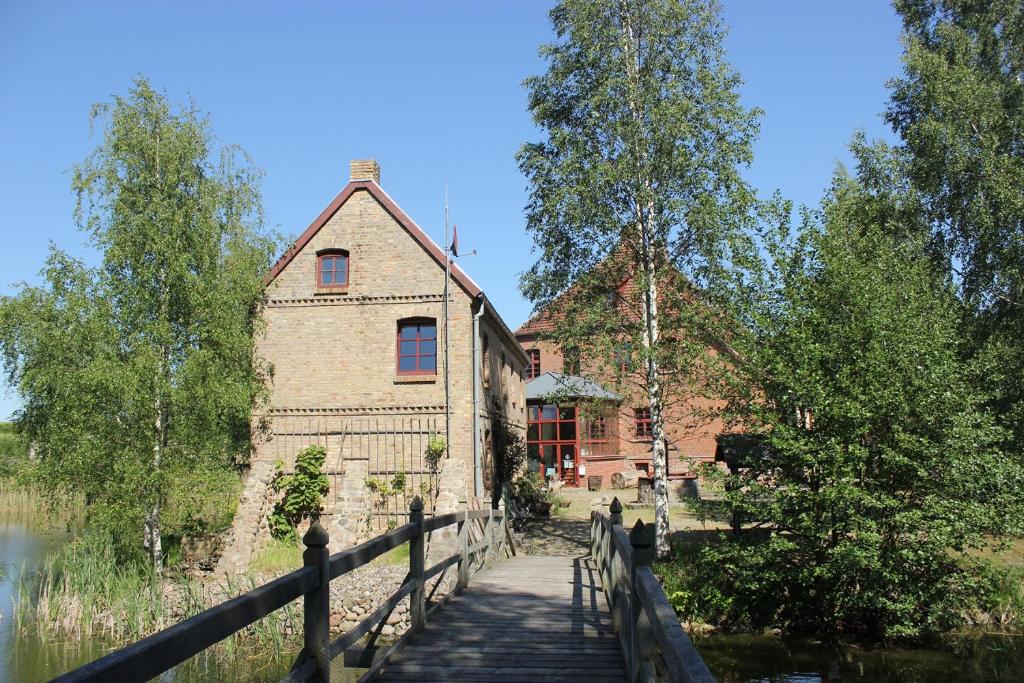 an old building with a bridge next to a lake at Rosenhaus der Wasserburg in Gielow