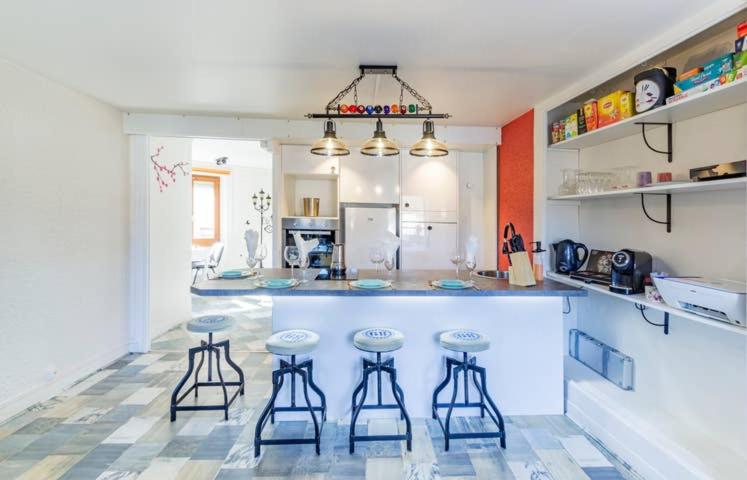 a kitchen with three bar stools and a counter at Chipote by Carl-Emilie in Épinal