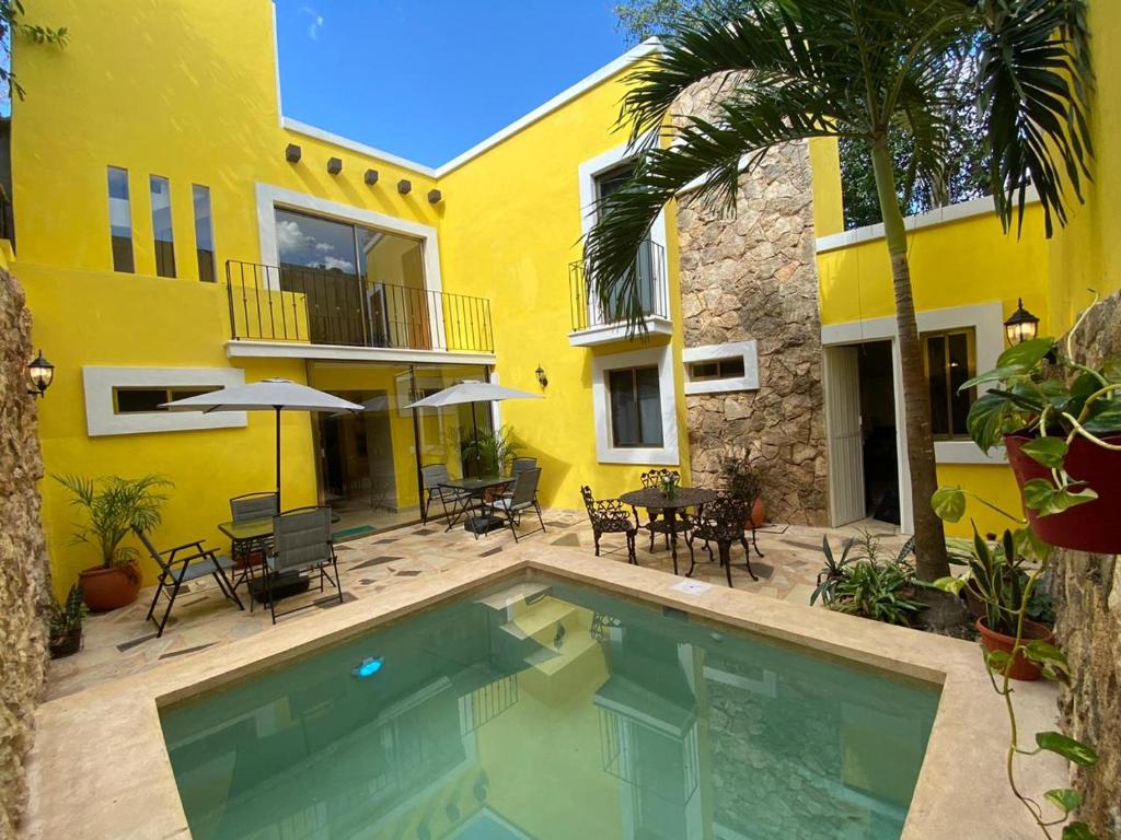 una casa amarilla con piscina frente a una casa en Los Candiles, en Valladolid