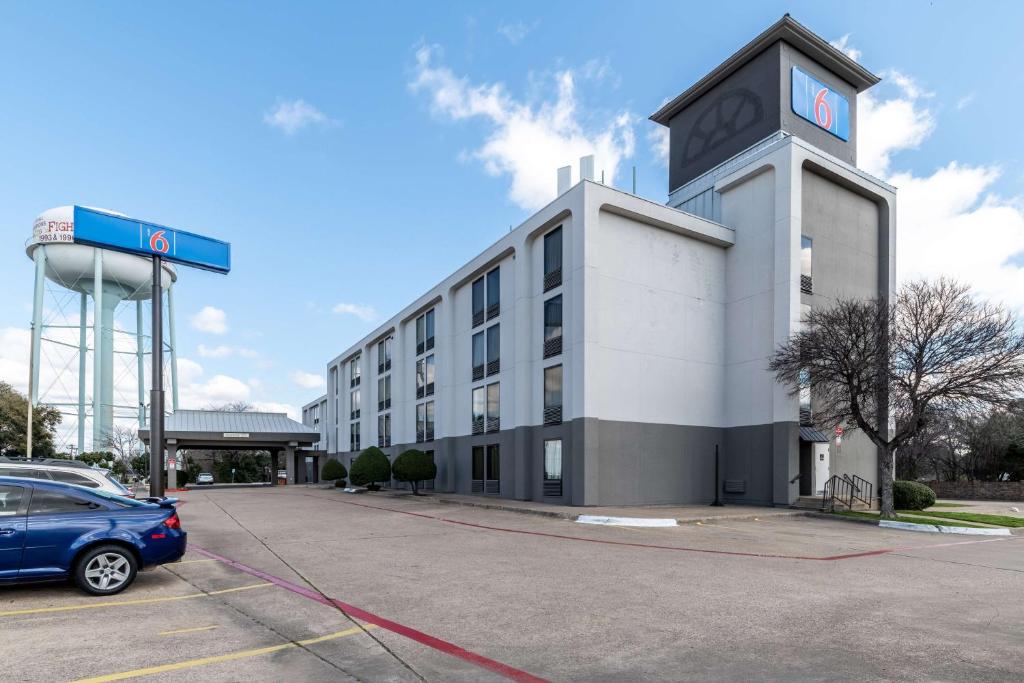 Motel 6-Lewisville, TX - Medical City في لويسفيل: مبنى فيه سيارة متوقفة في موقف للسيارات