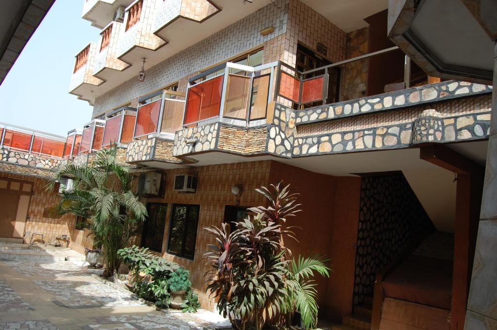 a building with balconies and plants in a courtyard at Benin Hotel Terminus in Cotonou