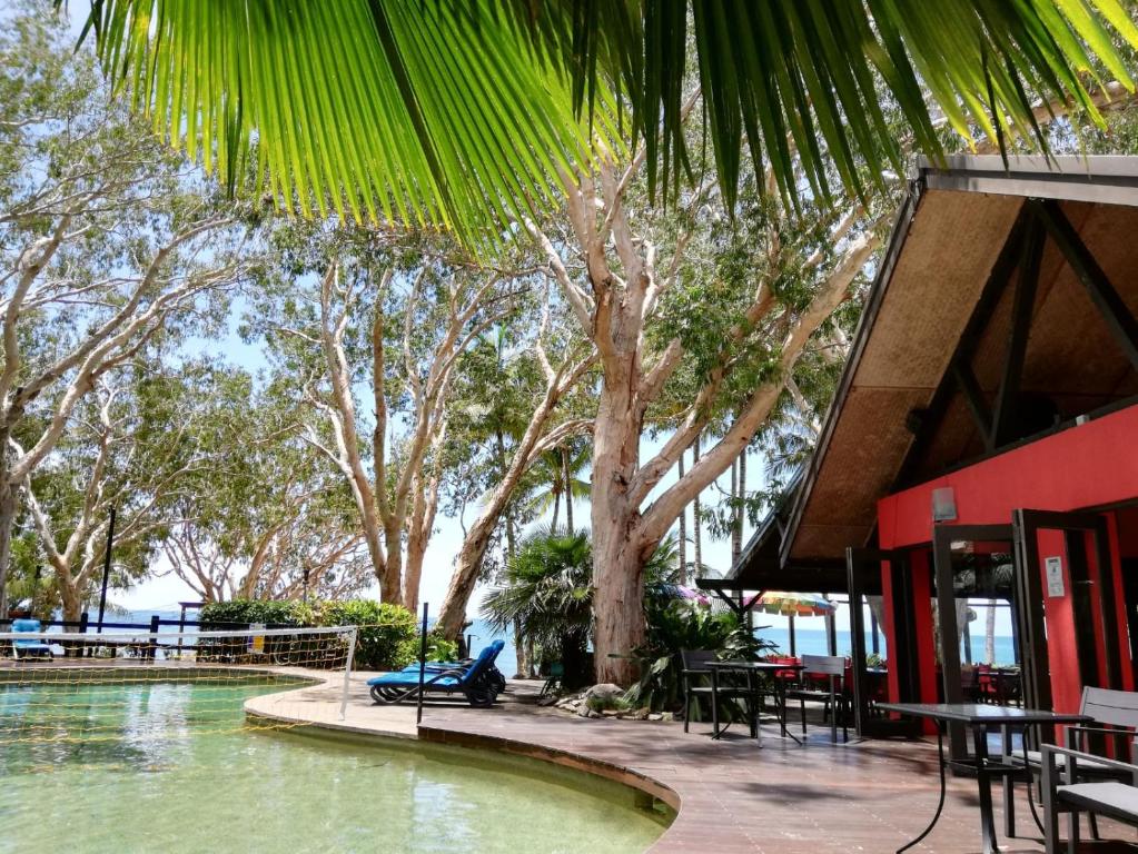 een resort met tafels en stoelen naast een waterlichaam bij Turtle Cove Beach Resort - Adults Only LGBTQIA & Allies in Oak Beach