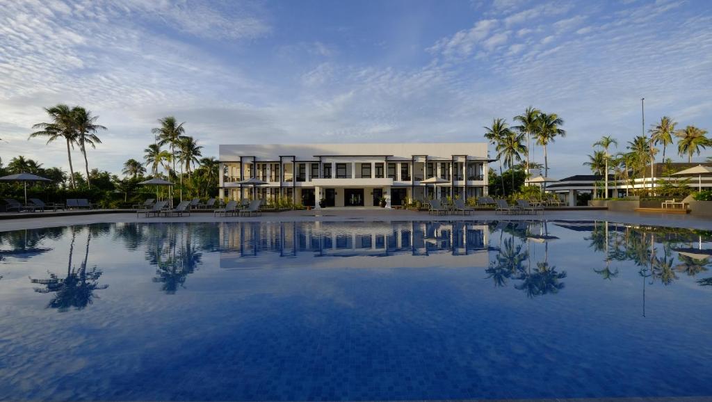 a large pool in front of a building with palm trees at Kandaya Resort in Daanbantayan