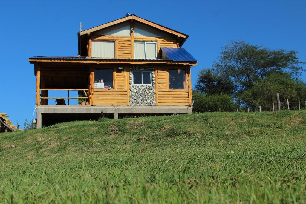 una casa de madera en la cima de una colina con césped en Amaneceres de San Isidro en José de la Quintana