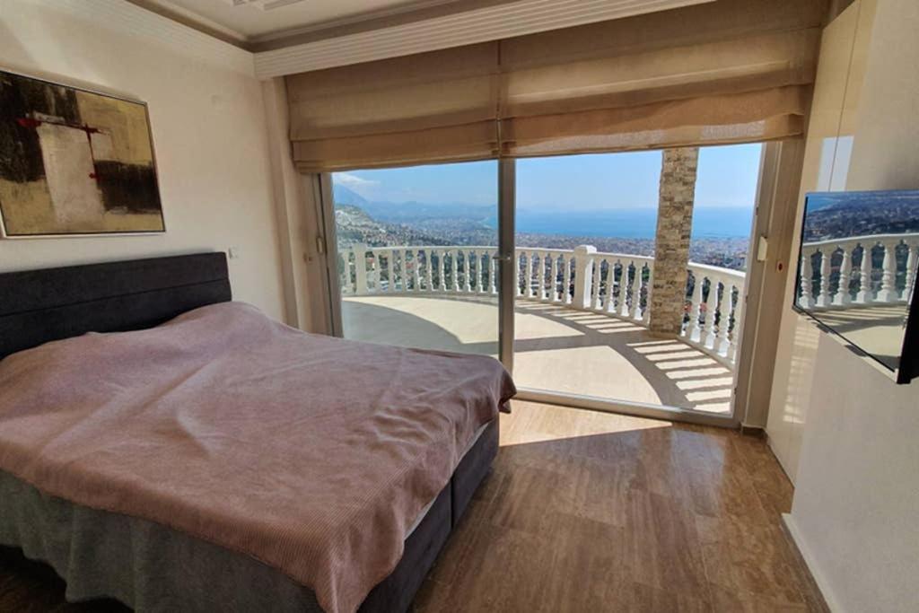 a bedroom with a bed and a balcony with a view at Уютная вилла с шикарным панорамным видом in Alanya