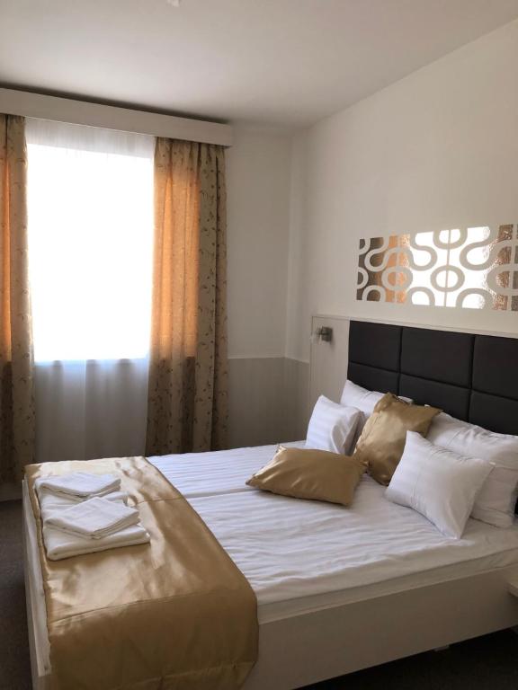 1 dormitorio con 1 cama grande con sábanas y almohadas blancas en Kerekes Panzió és Étterem, en Balmazújváros