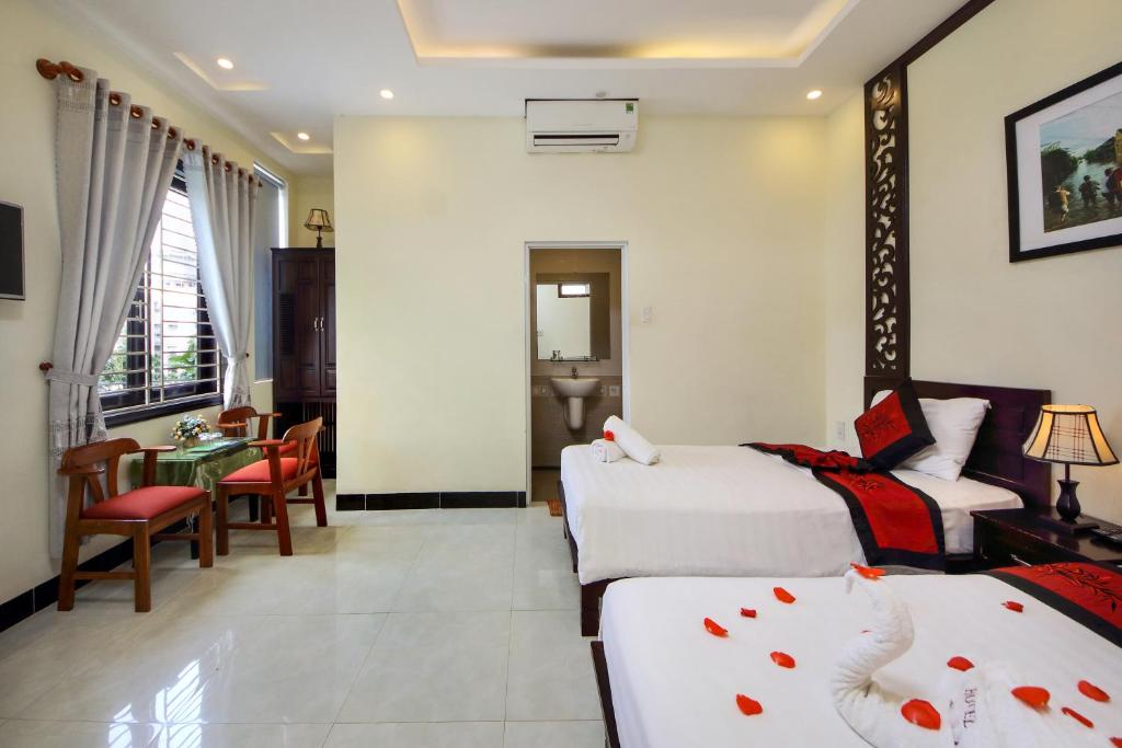 ein Hotelzimmer mit 2 Betten und einem Tisch in der Unterkunft Fireworks Homestay in Hoi An