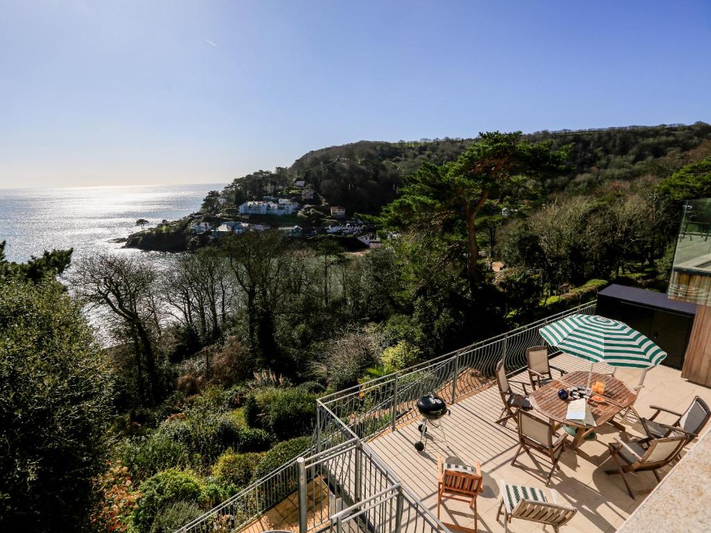 a balcony with a table and chairs and the ocean at Courtenay Villa in Salcombe