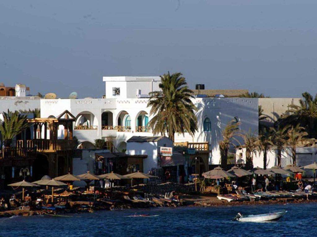 um resort com guarda-sóis e um barco na água em Planet Oasis Resort Dahab em Dahab