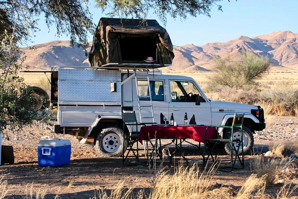 un camion blanc avec une tente en haut dans l'établissement Namib Desert Campsite, à Solitaire
