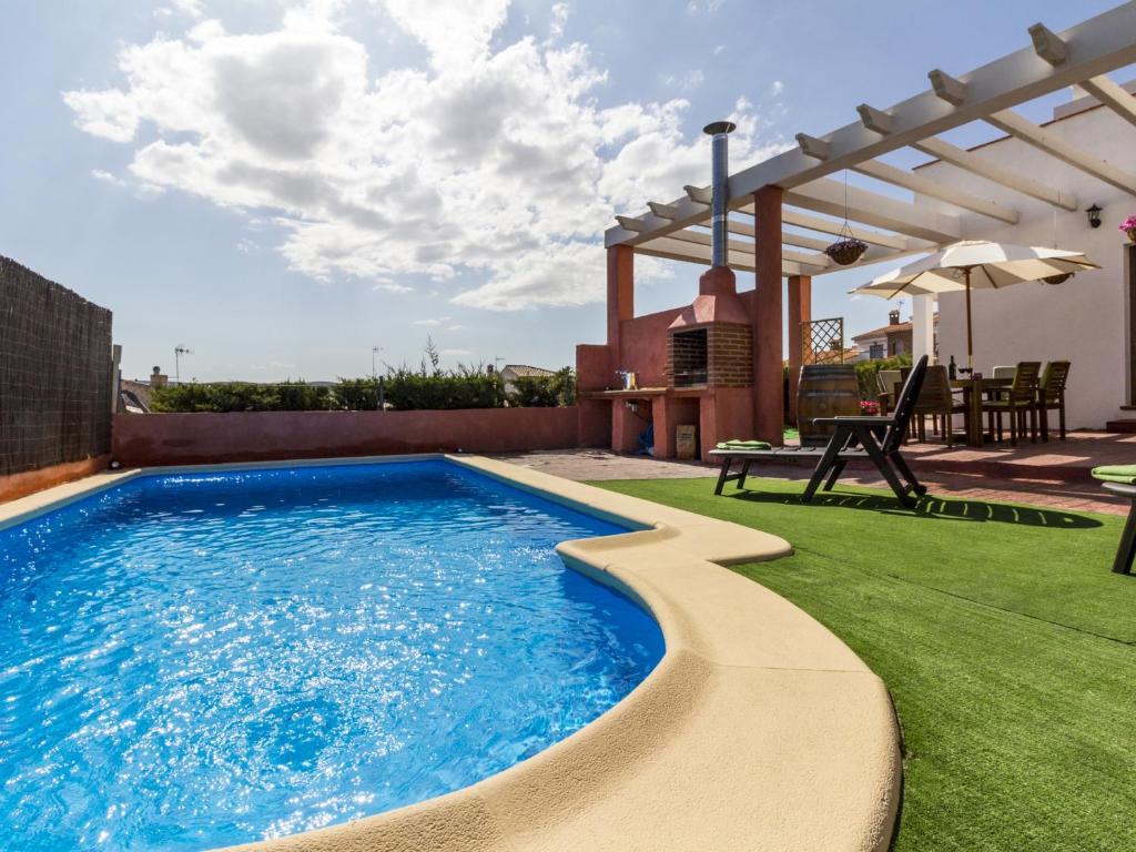 a swimming pool on a lawn with a pergola at Villa flor in Padul