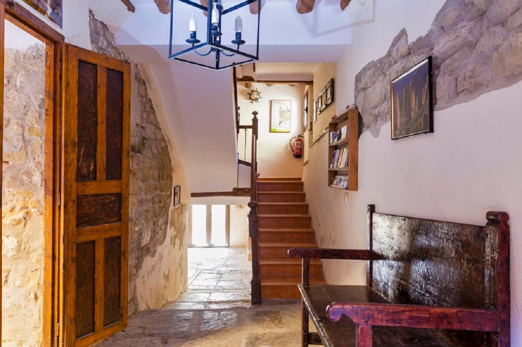 einen Flur mit einer Bank und eine Treppe mit einem Kronleuchter in der Unterkunft Apartamentos Casa Samper in Santa Eulalia de Gállego